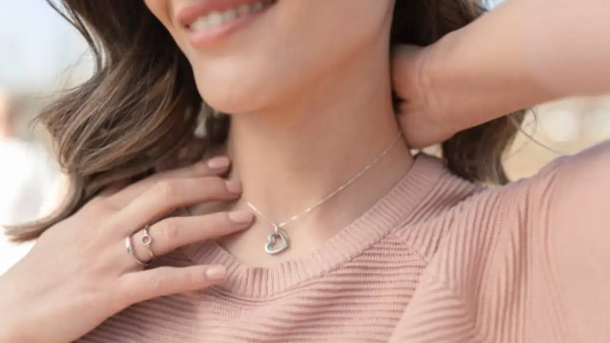beautiful woman putting on the silver necklace