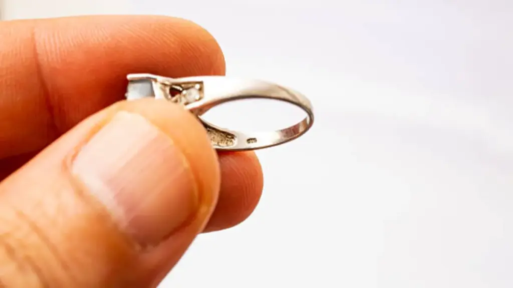 Male hand holding a silver ring and examining the markings close up on white background