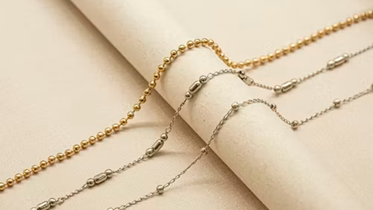 a roll of paper with a gold plated and silver chain on top of it